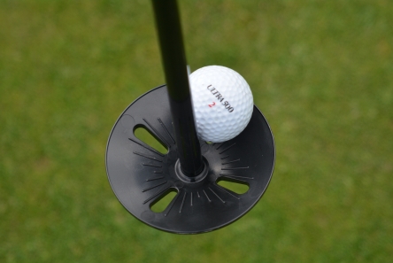 putting green flag with plastic ball tray in golf hole cup